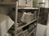 many pans and pans stacked on a shelf in a kitchen