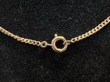 a gold chain with a clasp on a black velvet surface