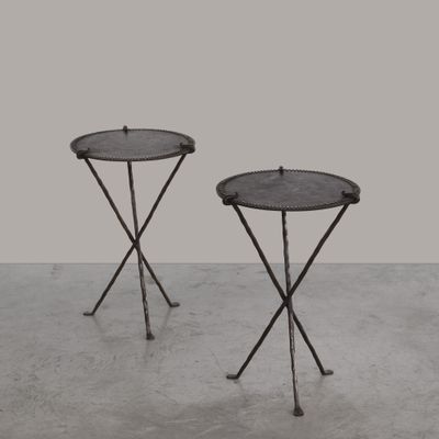 une paire de tables d'appoint en fer noir posées sur un sol en béton