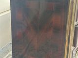 a small wooden chest of drawers sitting on a tiled floor