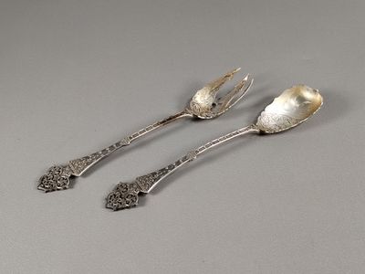 deux cuillères et une fourchette en argent sur une surface grise