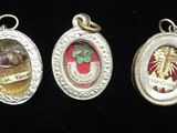 five different types of silver and enamel charms on a black background
