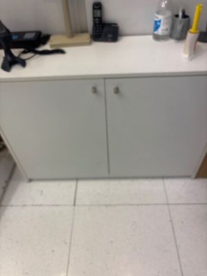 a white cabinet in the corner of a room with a phone on it
