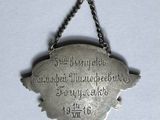 a metal plaque hanging from a chain on a wall