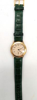 une image représentant une montre verte avec une chaîne en or sur fond blanc