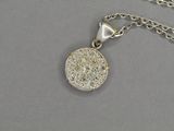 un gros plan d'un collier en argent orné d'un disque en diamant suspendu à une chaîne