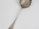 cuillère plaquée argent avec un manche en forme de coquillage sur un fond blanc