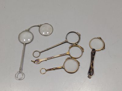 plusieurs paires de ciseaux et une loupe posés sur une table