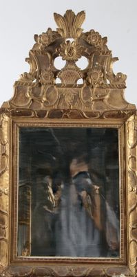 un miroir avec un cadre doré et un homme qui se prend en photo dedans