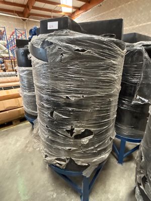 de nombreux rouleaux de plastique emballés sur une palette dans un entrepôt
