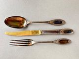 three spoons and a fork are sitting next to each other