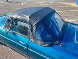 a blue car with a black top parked in a parking lot