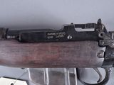 an old rifle with a wooden barrel on a stand with a tag attached to it