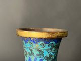 a blue vase with a gold rim sitting on a table
