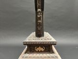an old bronze incense box with a wooden stand on a grey background