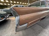 a brown car parked in a garage with other cars in the background