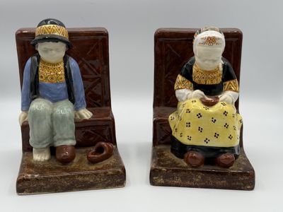 two figurines of a man and a woman sitting on a bench