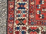a close up of a red and blue rug on a gravel ground