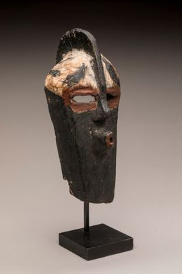 gros plan d'un masque en bois sur un support noir