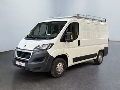 La camionnette blanche est garée dans une grande pièce au sol noir.