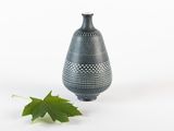 un vase noir avec une feuille verte à côté
