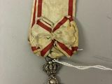 a close up of a red and white ribbon with a cross on it