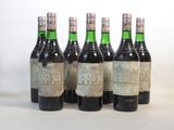six bouteilles de vin sont alignées sur une surface blanche