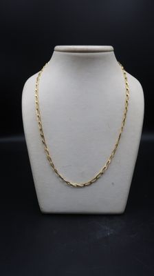 a white mannequin with a gold chain on it