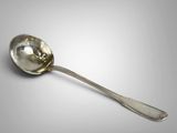 a silver spoon with a handle on a gray surface