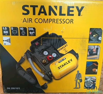 Le carton d'un compresseur d'air Stanley est ouvert et posé par terre.