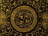 a close up of a black and gold plate with a gold design on it