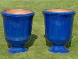 two blue vases sitting on the grass in the yard