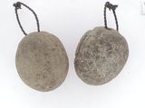 pair of stone balls with rope hangers on a white surface