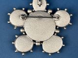a close up of a silver broochle on a blue background