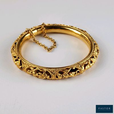 un gros plan d'un bracelet en or muni d'une chaîne, posé sur une surface blanche