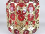 a red and gold vase sitting on a white surface