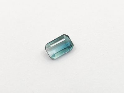a blue green tourmaline gems on a white surface