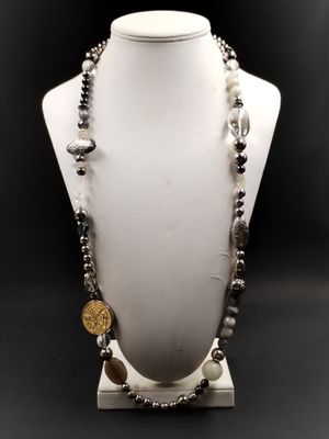 un mannequin blanc orné de perles noires et argentées et d'une pièce de monnaie