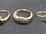 three gold rings with black stones on a black surface