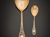 two spoons and a spoon rest on a black surface