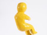 a yellow figurine of a man sitting on a chair