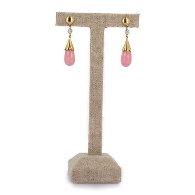 une paire de boucles d'oreilles roses et dorées posées sur un présentoir