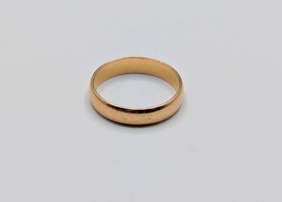 a close up of a gold wedding ring on a white surface