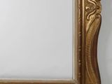 an ornate gold framed mirror on a white wall
