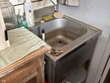 a sink in the corner of a room with a lamp on
