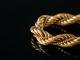 a close up of a gold bracelet with diamonds on a black surface