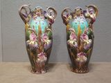 two vases with flowers painted on them sitting on a table