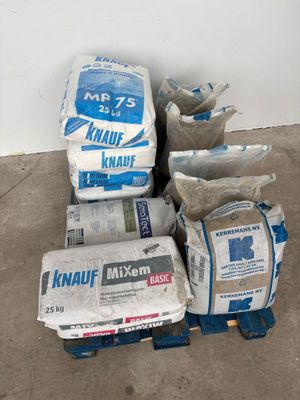 many bags of cement on a pallet next to a wall