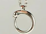 a close up of a silver necklace with a circular pendant on a chain