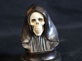 two figurines of a person with a skull on them